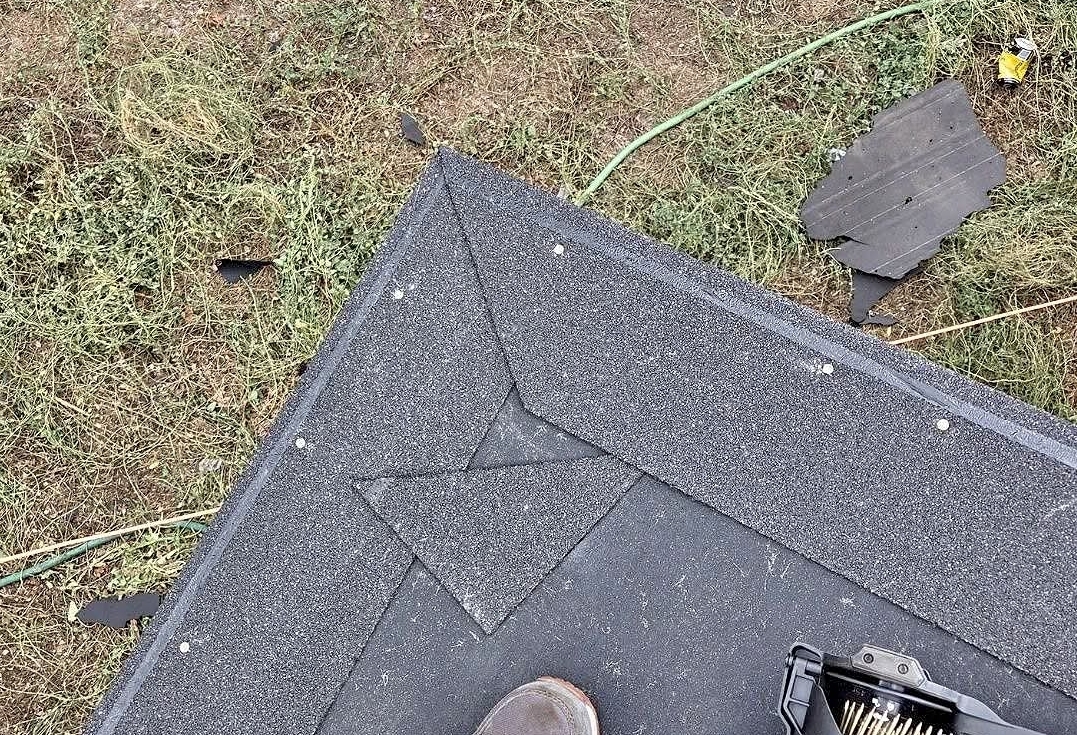 Starter strip angled-cut at a roof corner before shingles are installed, sealing the corner against wind