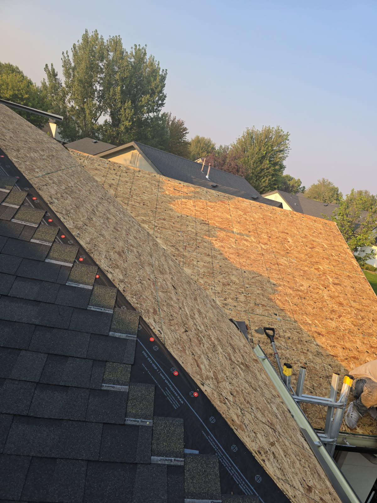 Roof midway through installation — shingles meeting fresh decking