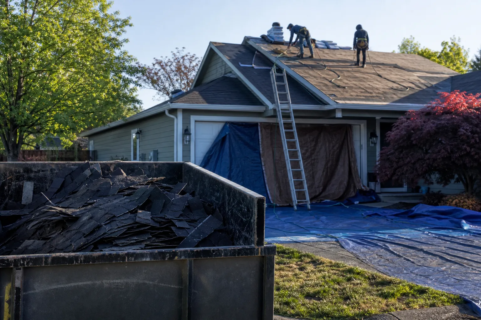 Torn-off shingle debris contained in a dumpster on a protected driveway